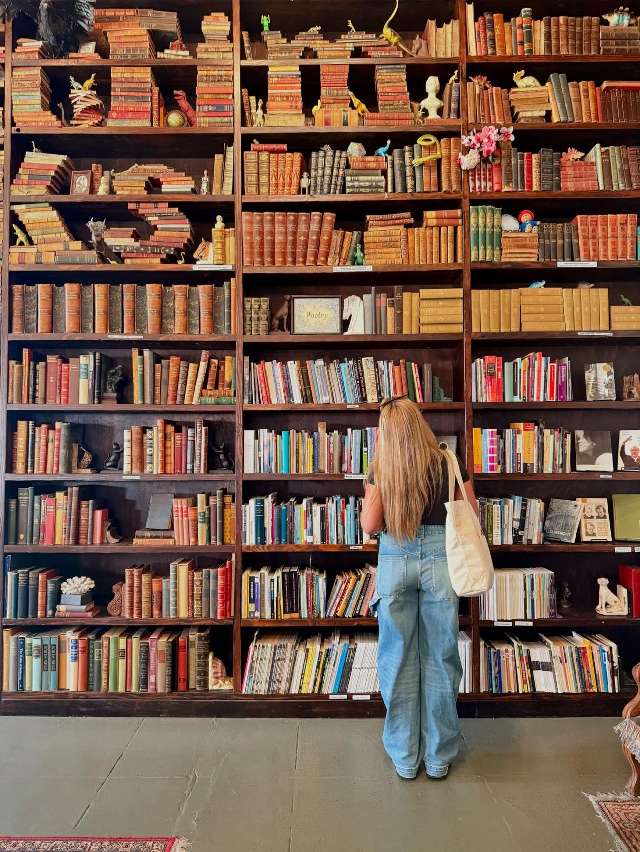 Tall packed bookshelves and a teal reading chair inside Verbatim Books